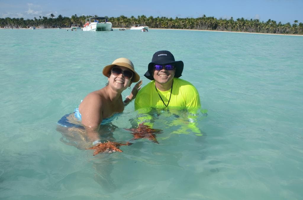 Travelers holding starfish in shallow Caribbean water
